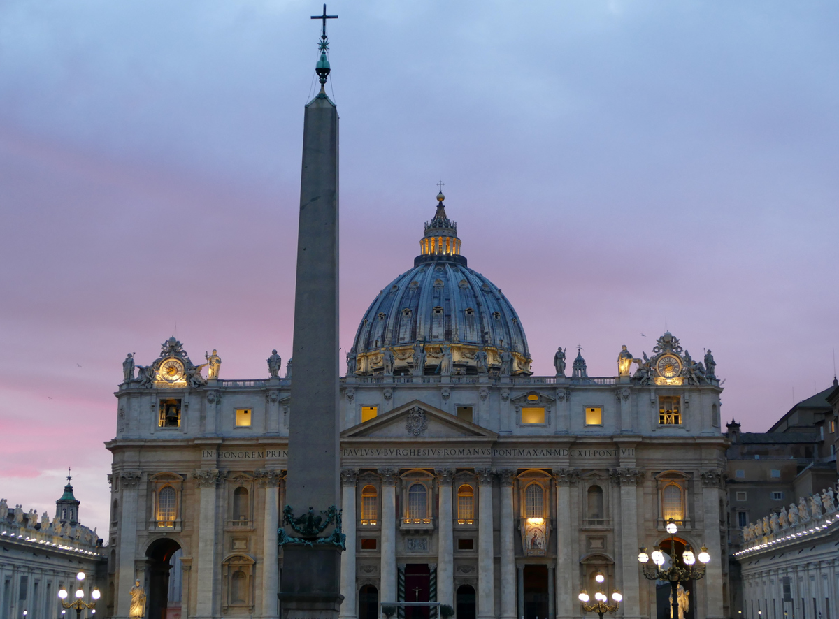 St. Peter's Basilica with the lights coming on and a dusky pink sky behind it